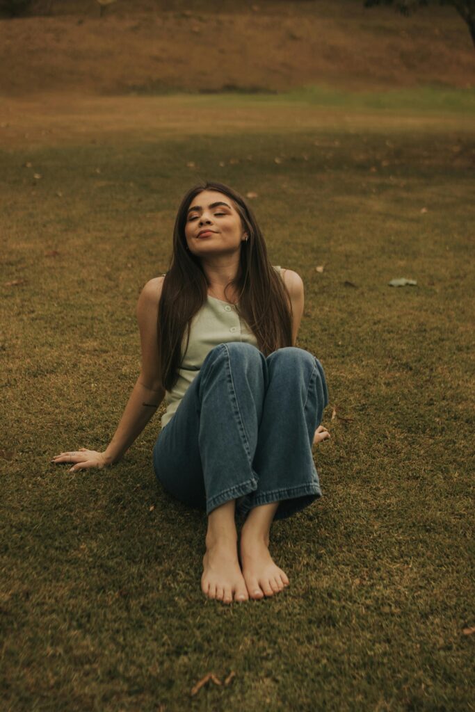 “Mulher sorrindo e relaxando ao ar livre, simbolizando leveza e bem-estar mental.”